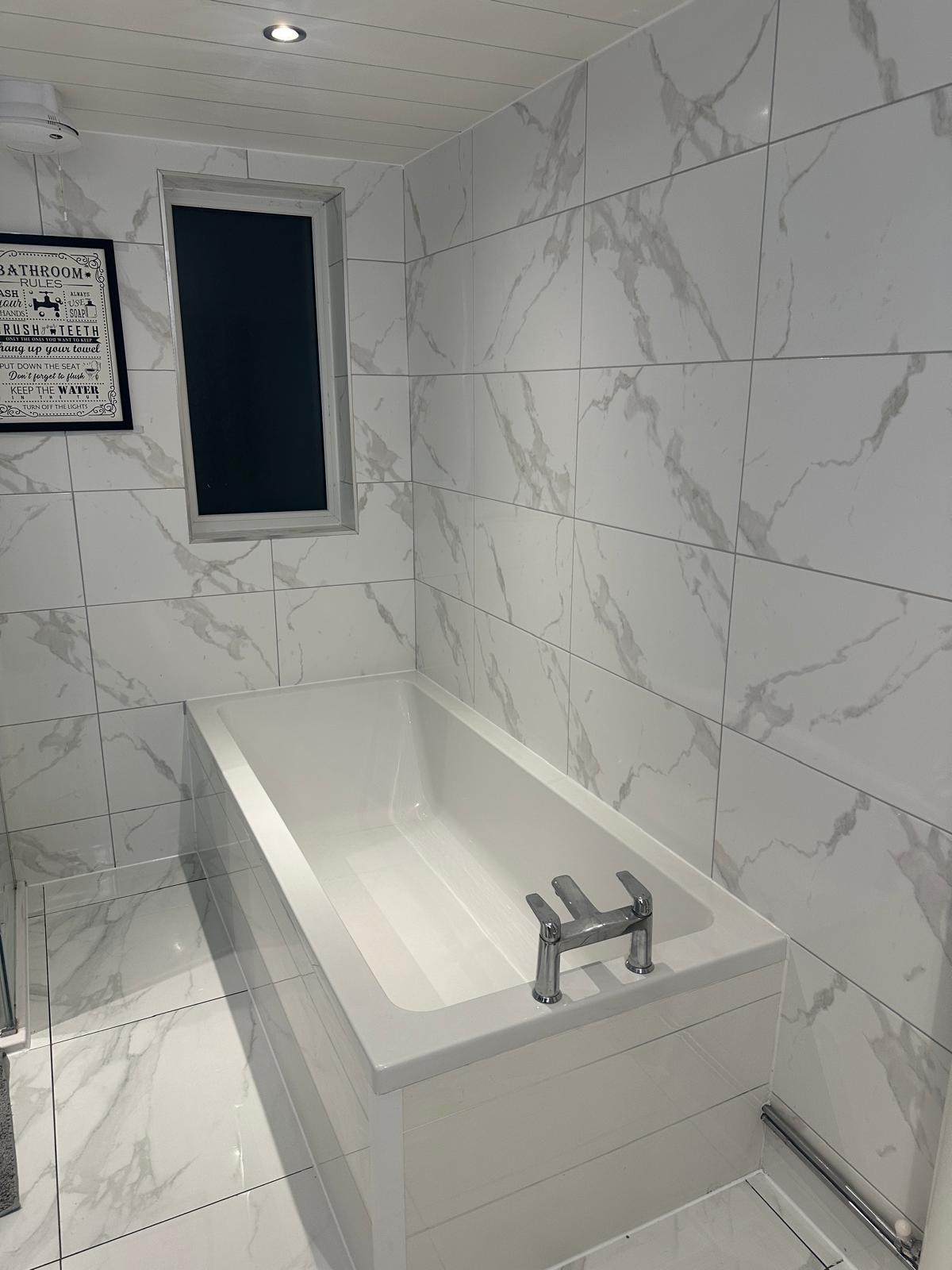 White bathtub against marble-effect tile in the Winter Park home